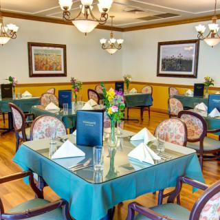 A well-decorated dining room with neatly arranged tables and elegant chandeliers.