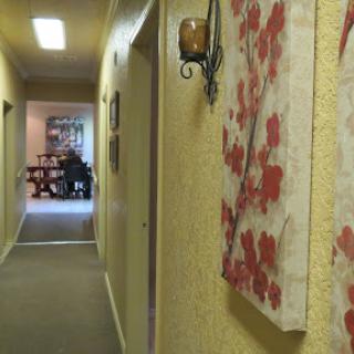 A view of a cozy hallway adorned with floral artwork, leading to a warmly lit room.
