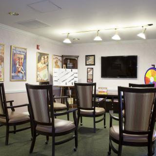 A well-lit conference room with arranged chairs, a television, and artwork on the walls.