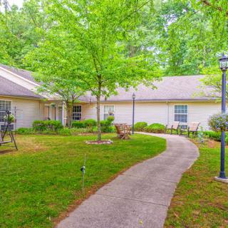 A peaceful garden with a pathway leading to a building surrounded by lush greenery.