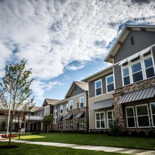A modern residential building with a landscaped courtyard under a partly cloudy sky.