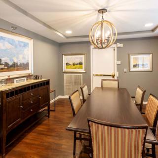 A modern dining room with a wooden table, upholstered chairs, and a stylish chandelier.