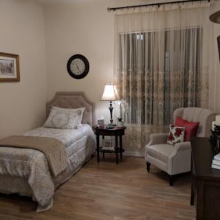 A cozy and well-decorated bedroom featuring a single bed, a comfortable armchair, and warm lighting.