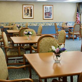 An empty dining room with tables, chairs, and floral centerpieces.