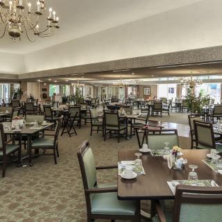 An elegant dining room with neatly arranged tables and chairs under chandeliers.