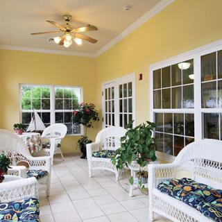 A bright sunroom with wicker furniture, yellow walls, and large windows.