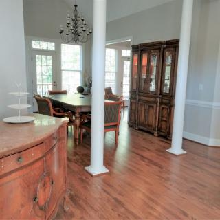 A spacious dining room with wooden floors, elegant furniture, and a chandelier.