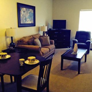 A cozy living room with a sofa, armchair, and a small dining area.