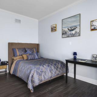 A cozy bedroom with a bed, a side table, and framed artwork on the walls.