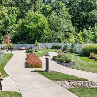 A beautifully landscaped garden featuring a winding pathway surrounded by lush greenery and well-maintained lawns.