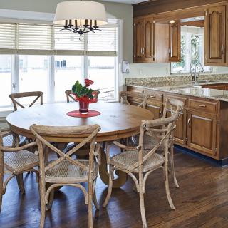A cozy kitchen and dining area with a round wooden table and elegant chairs, complemented by warm wood cabinetry and modern lighting.