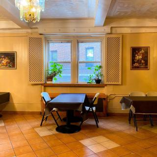 A cozy dining area with a table and chairs, plants by the window, and artwork on the walls.