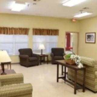 A cozy living room with armchairs, a sofa, a table, and lamps.