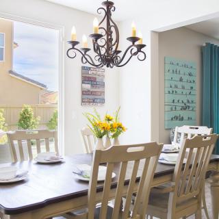A well-lit dining room with a wooden table, chairs, and a decorative chandelier.