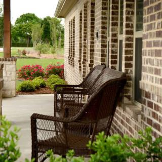 A cozy porch with wicker chairs facing a well-maintained garden.