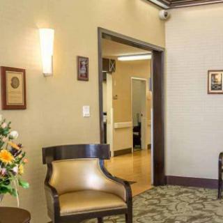 A cozy waiting room with chairs, a floral arrangement, and warm lighting.