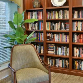 A cozy reading nook with a chair and bookshelves in a well-lit room.