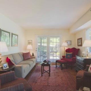 A cozy living room with a comfortable sofa and armchair, illuminated by lamps and decorated with framed pictures.