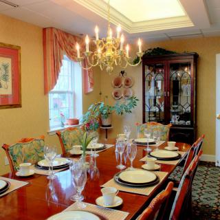 A well-appointed dining room with a chandelier, elegant table settings, and a china cabinet.
