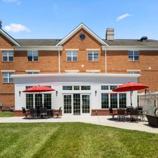 A brick residential building with a patio and well-maintained lawn.