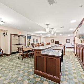 A spacious and well-lit lobby area featuring a wooden bar and elegant dining furniture.