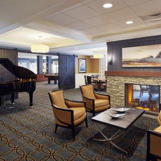 A cozy hotel lounge featuring a fireplace, piano, and comfortable seating.