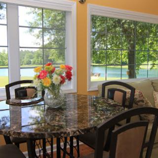 A bright and inviting dining area with a beautiful lake view, featuring a floral centerpiece on the table.
