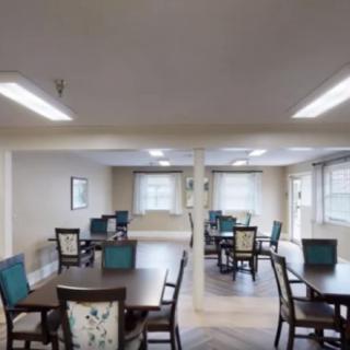 A spacious dining area with several tables and chairs, well-lit with natural light.