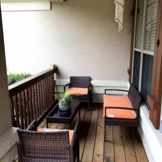 Cozy outdoor seating area with wicker furniture and orange cushions on a patio.