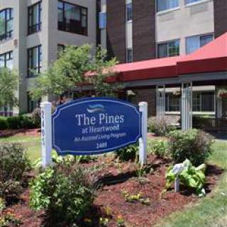 Entrance of The Pines at Pinecrest featuring a landscaped sign and modern building.