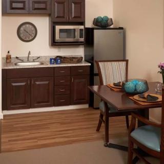 A cozy kitchen and dining area featuring dark wood cabinetry, a compact refrigerator, a microwave, and a small dining table with chairs.