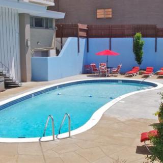 A sunny day at an outdoor swimming pool with surrounding patio furniture.
