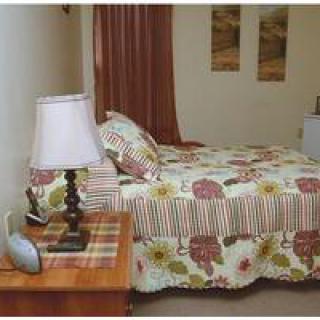 A cozy bedroom with floral patterned bedding and a wooden nightstand.