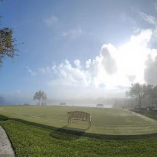A serene park scene with a bench overlooking a misty landscape under a bright sky.