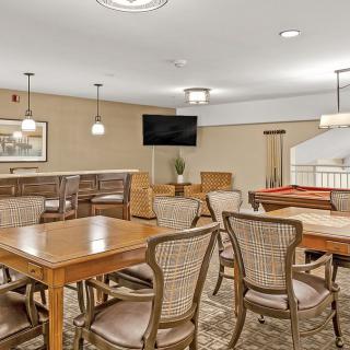 A cozy dining area featuring wooden tables and chairs, a television, and decorative artwork on the walls.