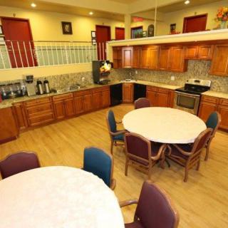 A spacious kitchen and dining area with wooden cabinets, round tables, and various chairs.