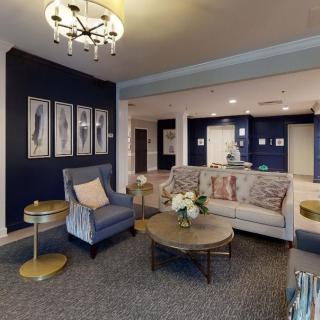 A cozy living room with modern decor, featuring a sofa and armchair, accented by a chandelier.
