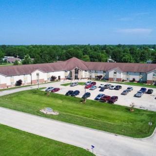 Aerial view of a large building with a parking lot surrounded by greenery.