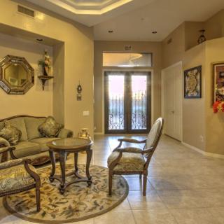 A cozy living room with elegant furniture and decor, featuring a sofa set, chairs, and a round table on a decorative rug near the entrance.