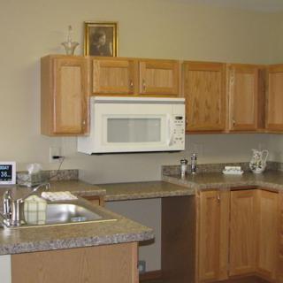 A kitchen with wooden cabinets, a microwave, and a countertop with a sink.