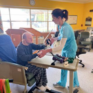 A nurse assisting an elderly patient with rehabilitation exercises in a healthcare setting.