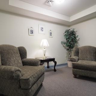 A cozy seating area featuring two comfortable armchairs, a small table, and a lamp, complemented by decorative wall art and indoor greenery.