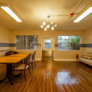 A cozy dining area with a wooden table, chairs, and a sofa, illuminated by overhead lighting.