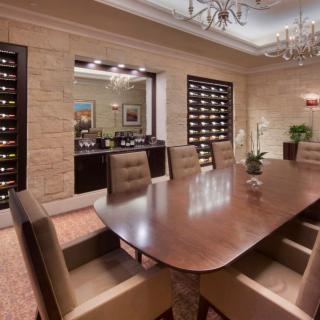 A luxurious dining room with an elegant wooden table and wine cellar displays.