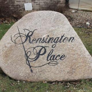 A large rock with 'Kensington Place' written in decorative script.