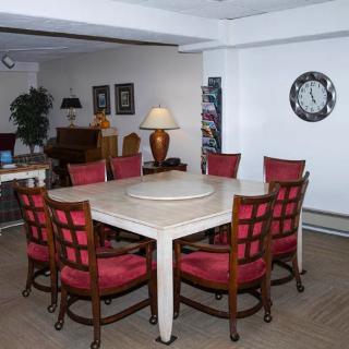 A dining room with a large square table surrounded by red cushioned chairs and stylish decor elements.