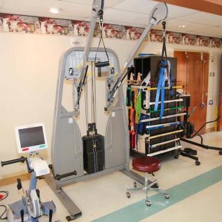 A medical facility room equipped with various rehabilitation and exercise machines for physical therapy.