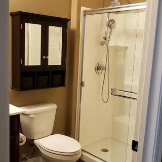 A modern bathroom with a glass shower enclosure and a wall-mounted cabinet above the toilet.