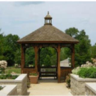 A wooden gazebo surrounded by a garden pathway.