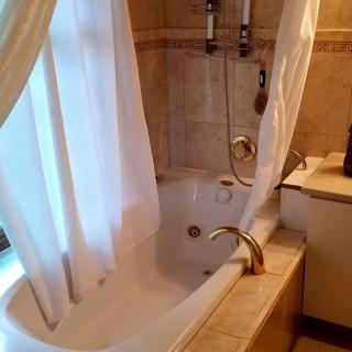 A cozy bathroom with a bathtub and shower setup, featuring a curtain and tiled walls.